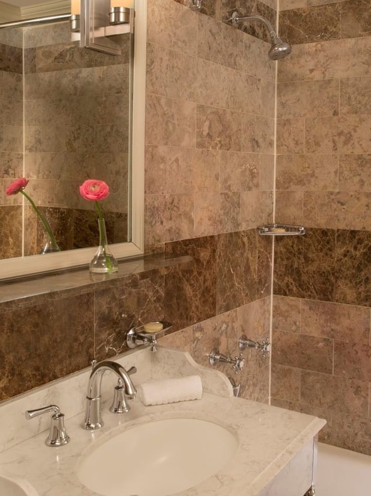Premier City View bathroom with brown marble tiles with white vanity, and a glass-enclosed shower at Warwick New York