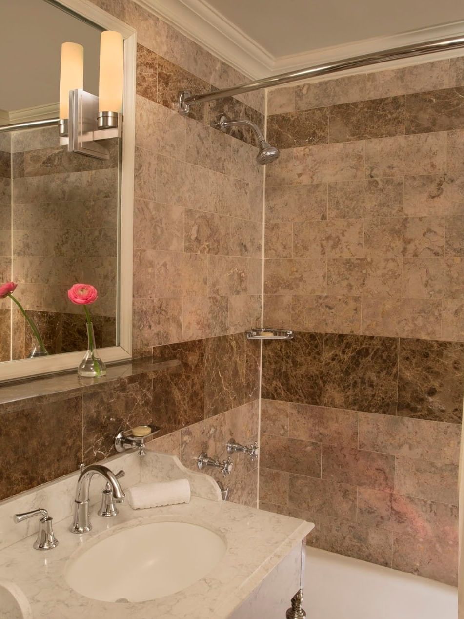 Premier City View bathroom with brown marble tiles with white vanity, and a glass-enclosed shower at Warwick New York