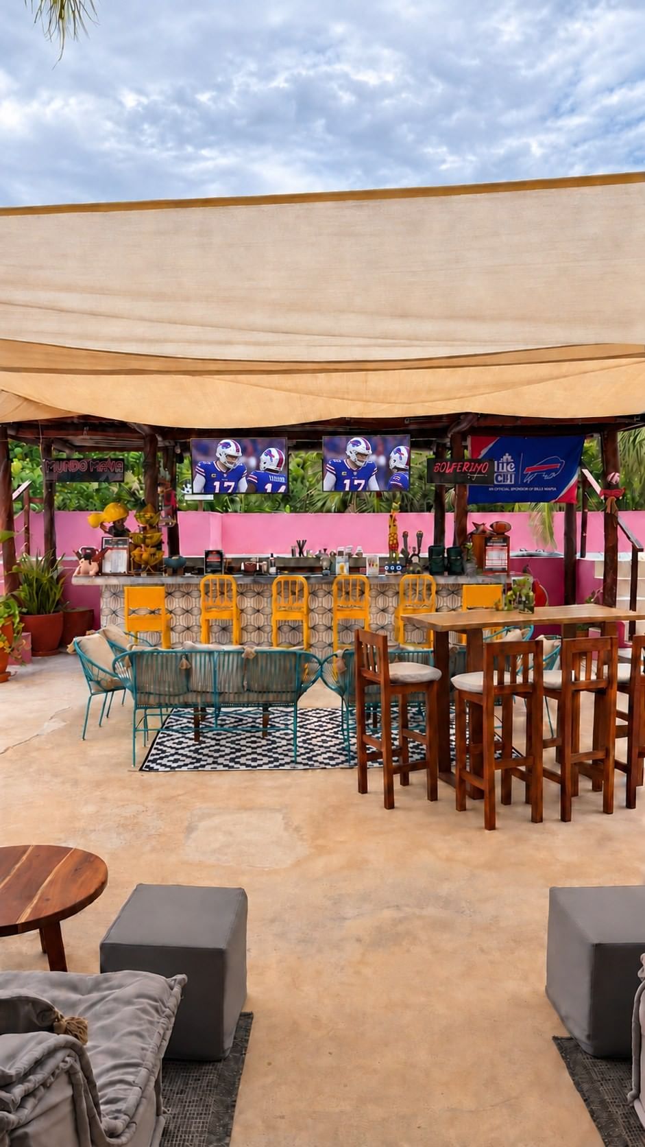 La Zebra’s bar counter with yellow stools, shared tables and two screens showing football.