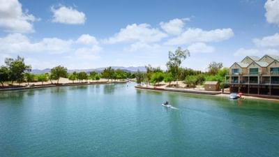 Waterfront view with jet skier on turquoise canal lined by trees and resort buildings at London Bridge Resort