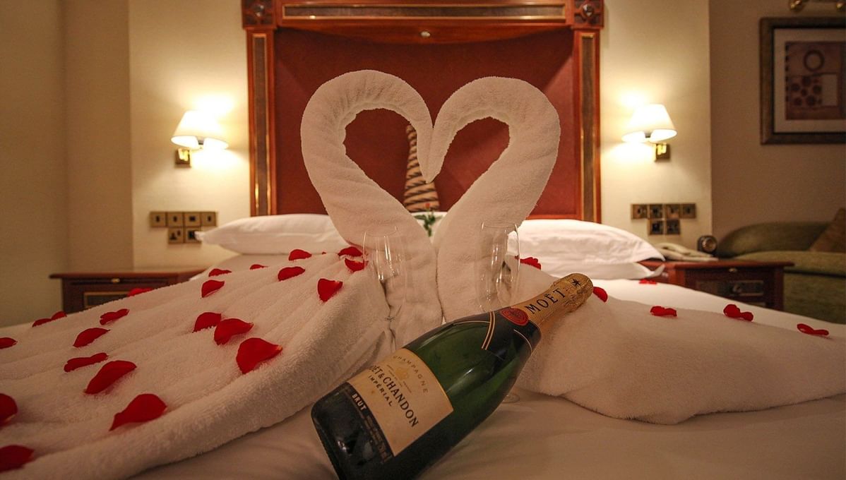 Champagne and rose petals on a bed at Kigali Serena Hotel