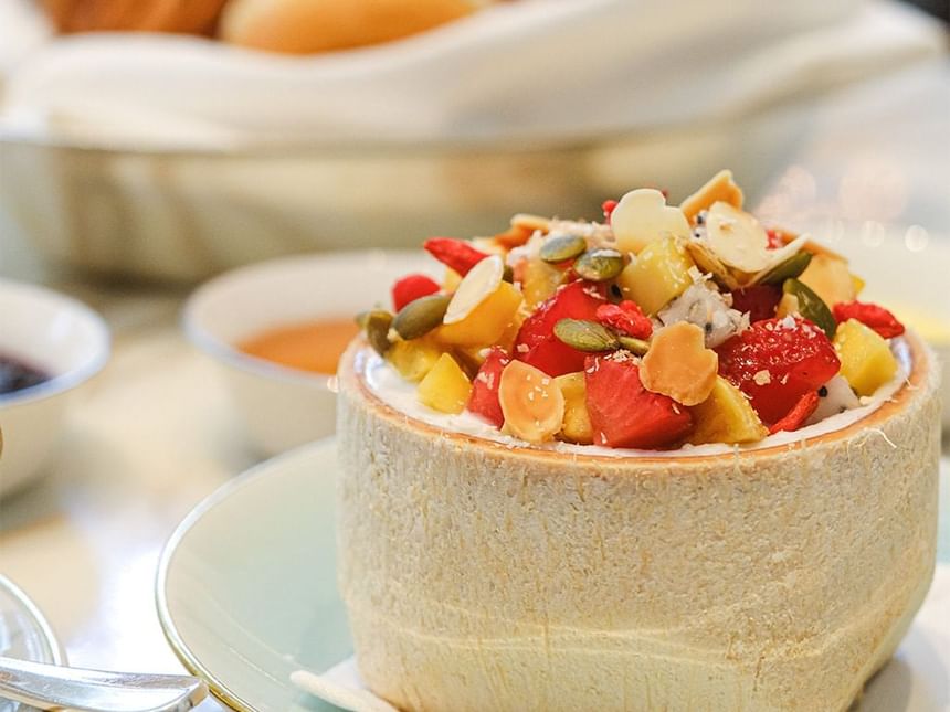 Coconut bowl filled with colorful diced fruits, nuts, and seeds in Park Lounge at Park Hyatt Saigon
