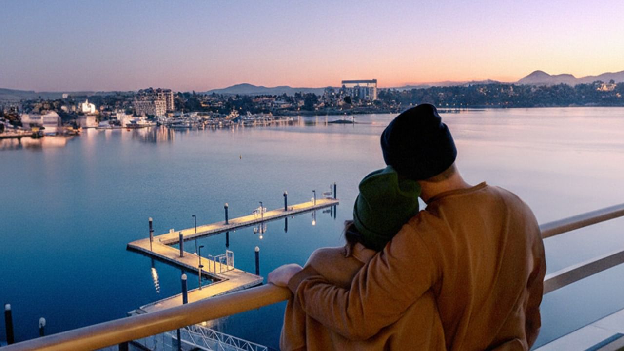 Couple standing arm in arm overlooking a waterfront cityscape at sunset