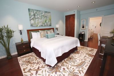 Imperial Penthouse with a large bed, blue walls, floral rug, and a painting above the bed.