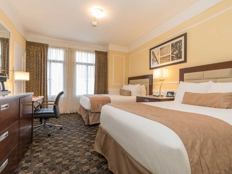 Two beds, desk, and dresser in a hotel room at Pickwick San Francisco.
