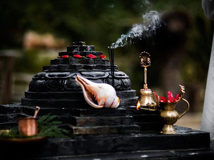 Hindu altar with a black stone Shivalinga, adorned with rose petals, near Dwarika's Himalayan Wellbeing