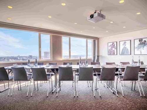 Meet 26 Four Meeting room with tables, chairs, and city view through large windows at The Hotel Brussels