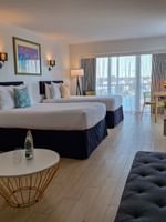 Harbour Premium Balcony with two beds by a sofa under wall lamps near a long desk at Warwick Paradise Island Bahamas