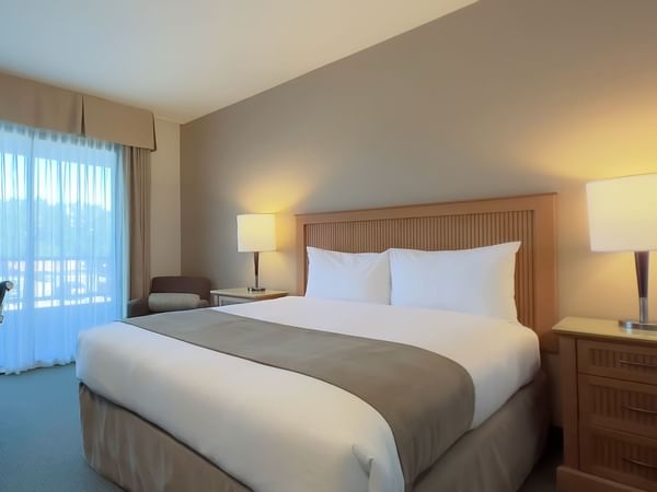 Guest room with queen bed, desk, lamps and television
