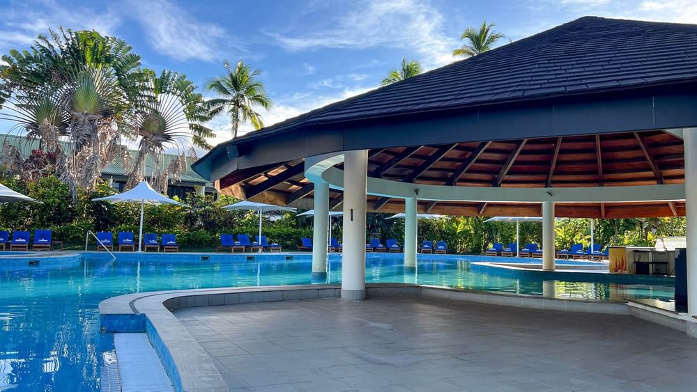Swimming pool with blue water and cabanas at The Naviti Resort in Korolevu, Fiji.