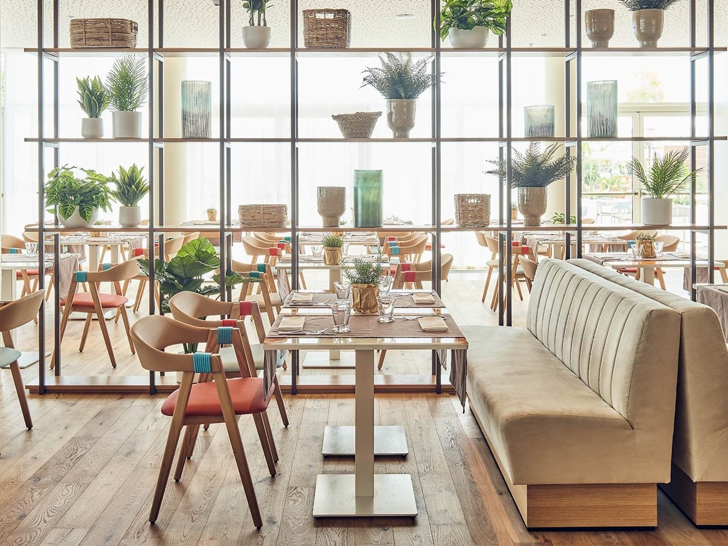 Artigiani Restaurant & Market interior with wooden floors, dining tables, and decorative shelves at Falkensteiner Hotel & Spa Jesolo in Jesolo.