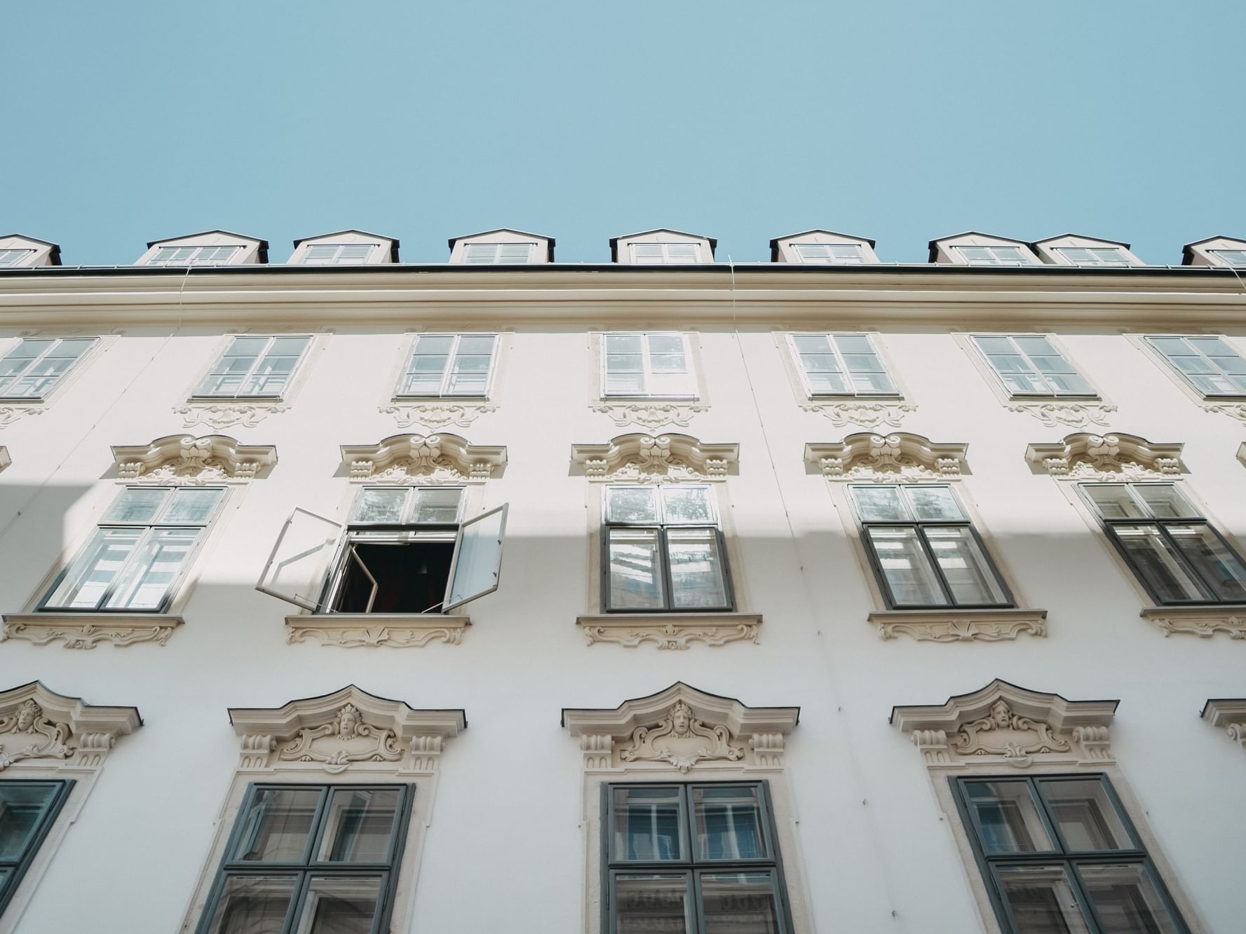 THE LEO GRAND facade with many windows and ornate detailing, one window is open, under a clear blue sky.