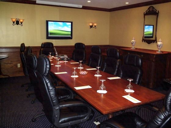 meeting room with table, desk chairs and television on wall