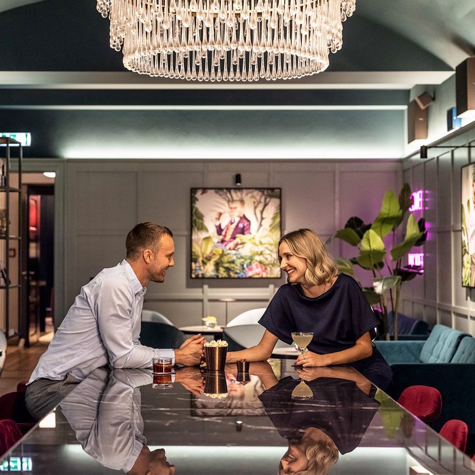 A couple dining in an elegant room with plush furnishings at Falkensteiner Hotel Prague