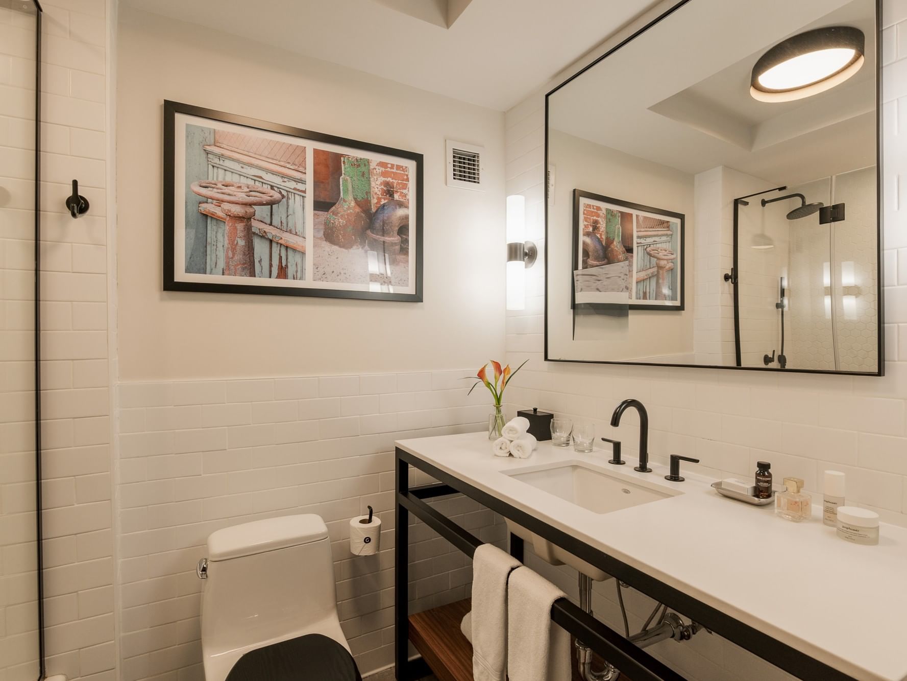 Modern accessible bathroom with white tiled walls, sink, toilet, and mirror at Gansevoort Meatpacking NYC, New York.