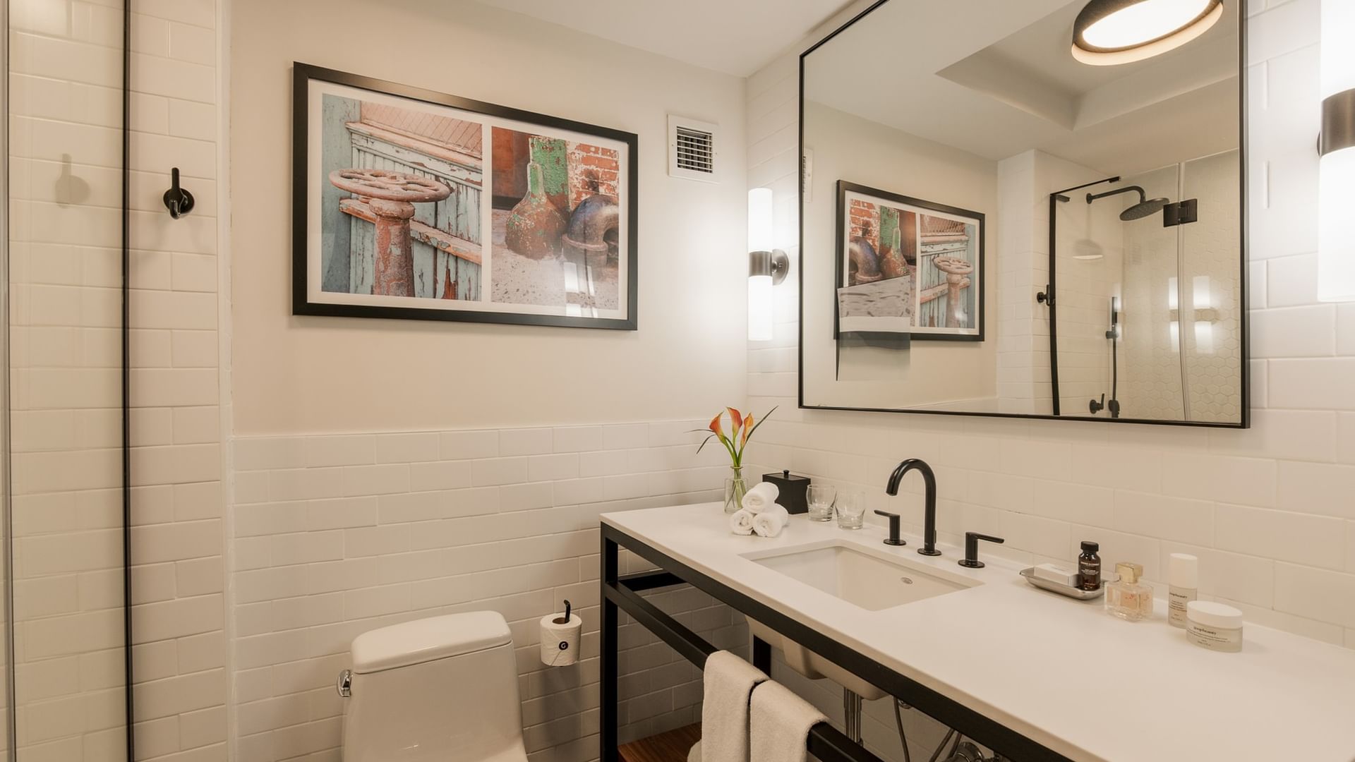 Modern bathroom with white subway tile, black-framed mirror, vanity with white countertop at Gansevoort Meatpacking NYC - NEW.