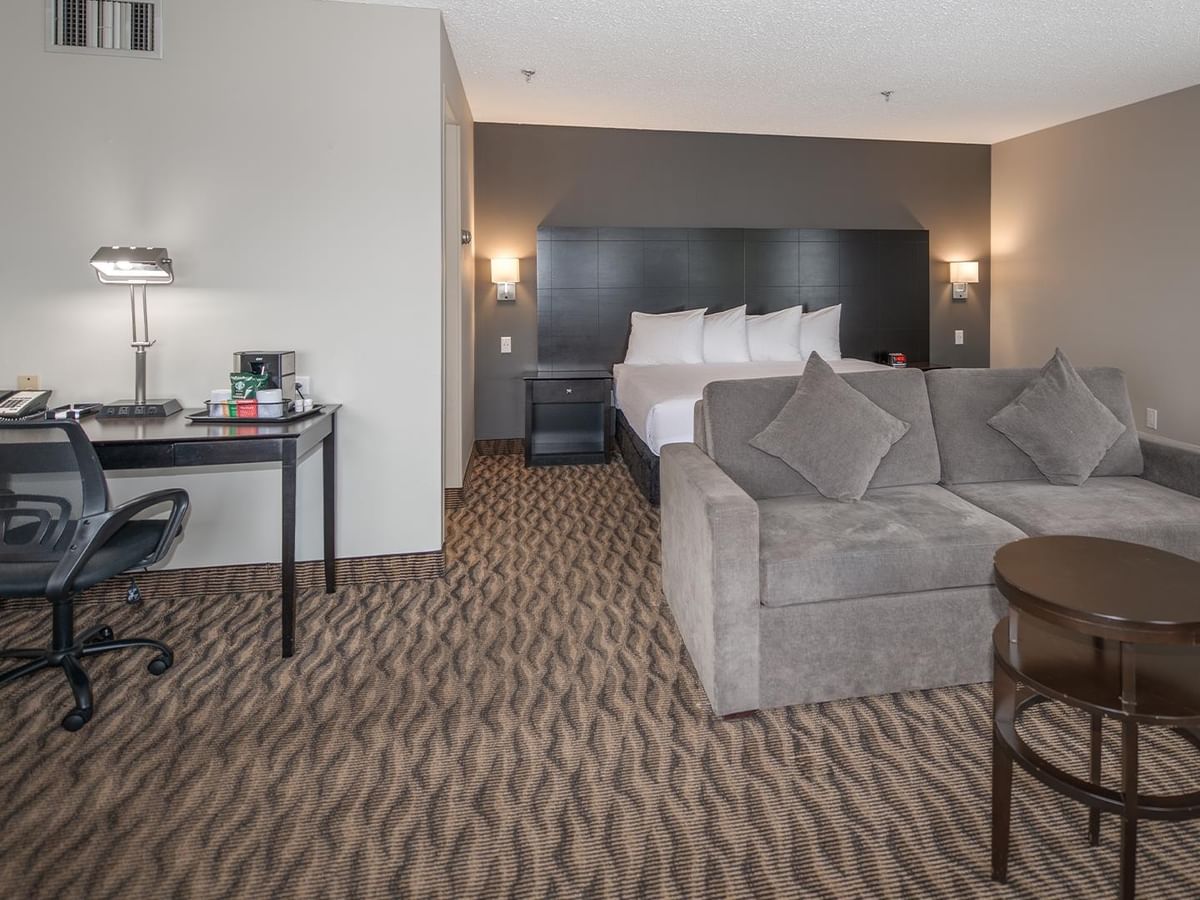 Living area with couch and desk in a hotel suite.