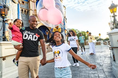 Family holding hands and walking in a theme park with balloon near Lake Buena Vista Resort Village & Spa