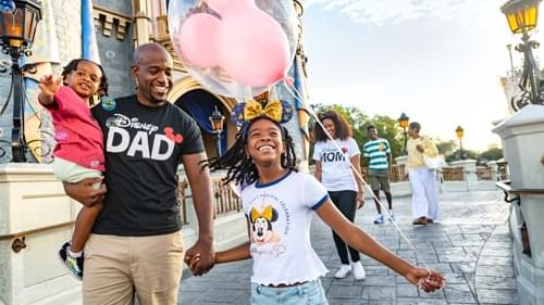 Family holding hands and walking in a theme park with balloon near Lake Buena Vista Resort Village & Spa