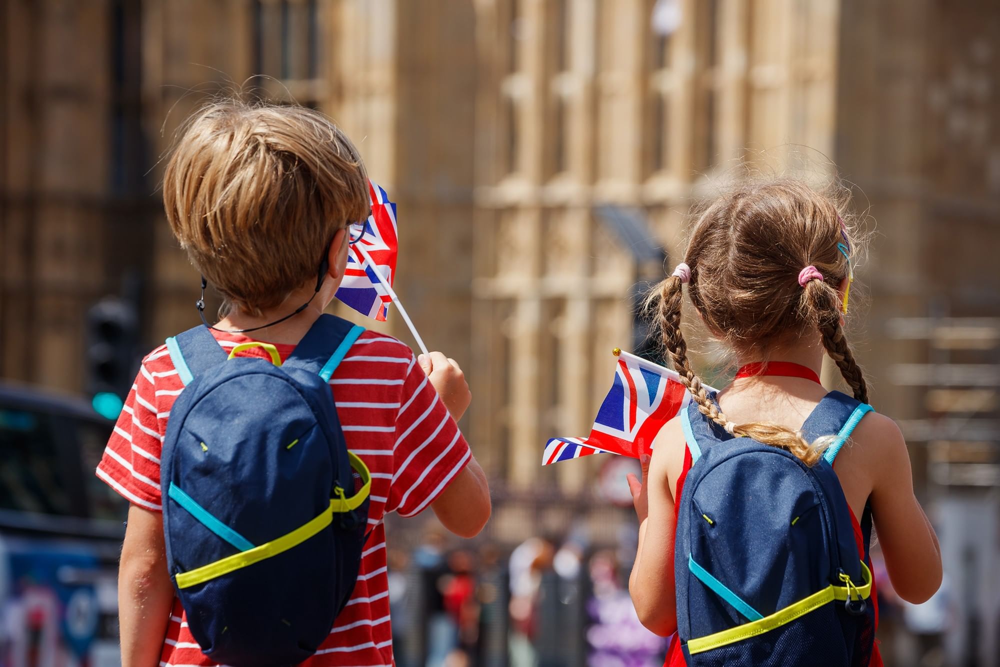 Two children holding small flags by a stone building facade near The Capital Hotel, Apartments and Townhouse
