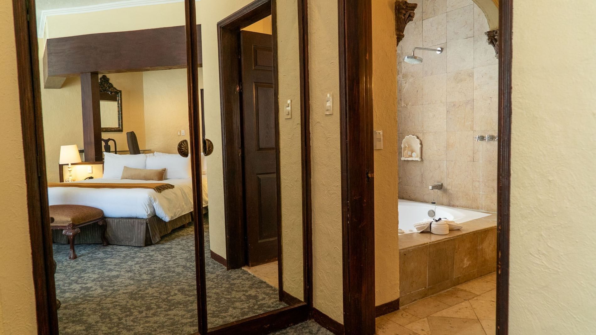 King Governor Suite featuring a mirrored closet and a view into a stone bathtub at Quinta Real Aguascalientes