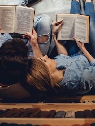 Top view of couple lounging close together while reading books at Cove Pocono Resorts