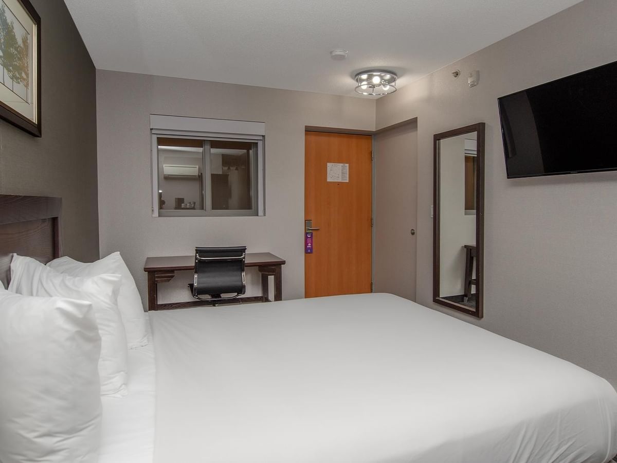 Hotel room with bed, desk, and TV.