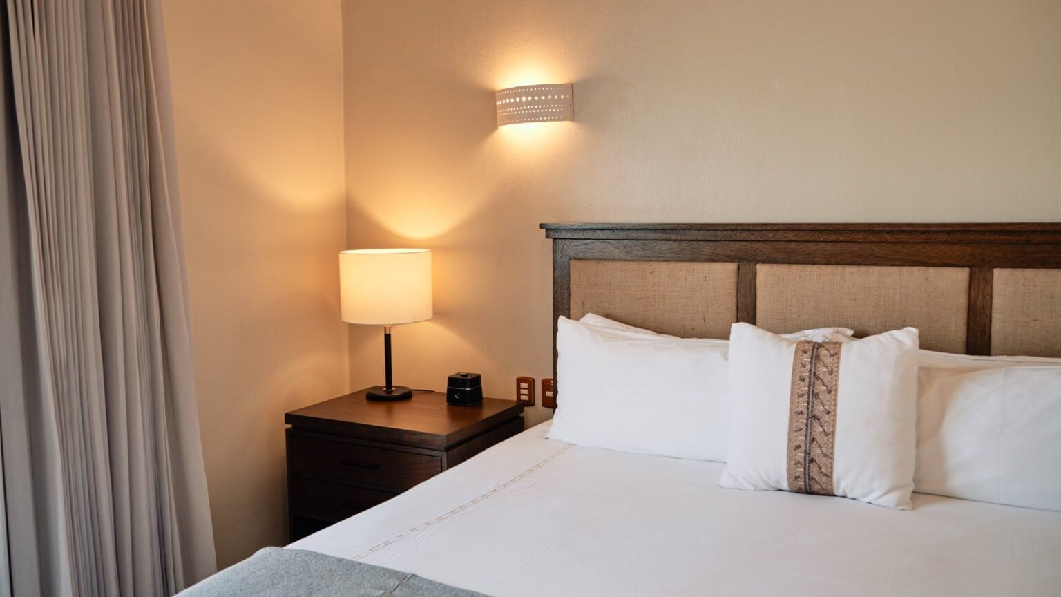 Cozy room featuring a comfortable bed with a decorative headboard and bedside lamp at Curamoria Collection