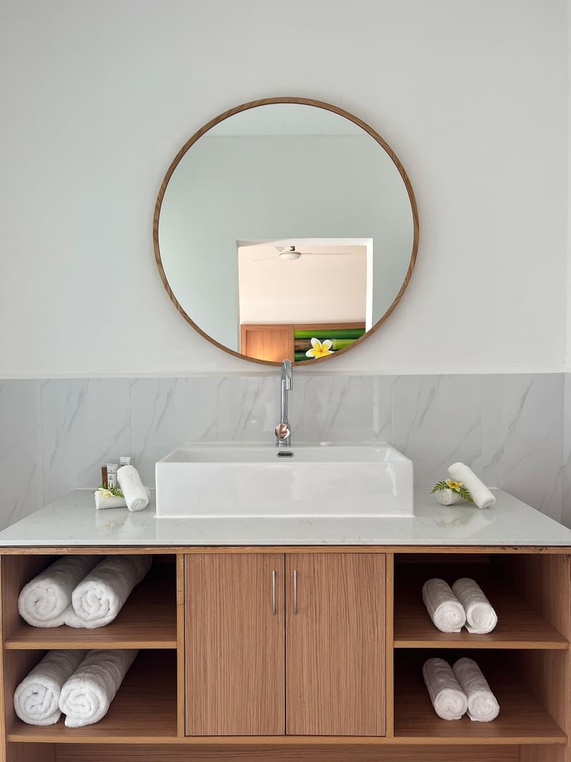 White bathroom with wooden cabinets, large mirror, and folded towels at Warwick Le Lagon - Vanuatu, Efate.