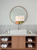 White bathroom with wooden cabinets, large mirror, and folded towels at Warwick Le Lagon - Vanuatu, Efate.