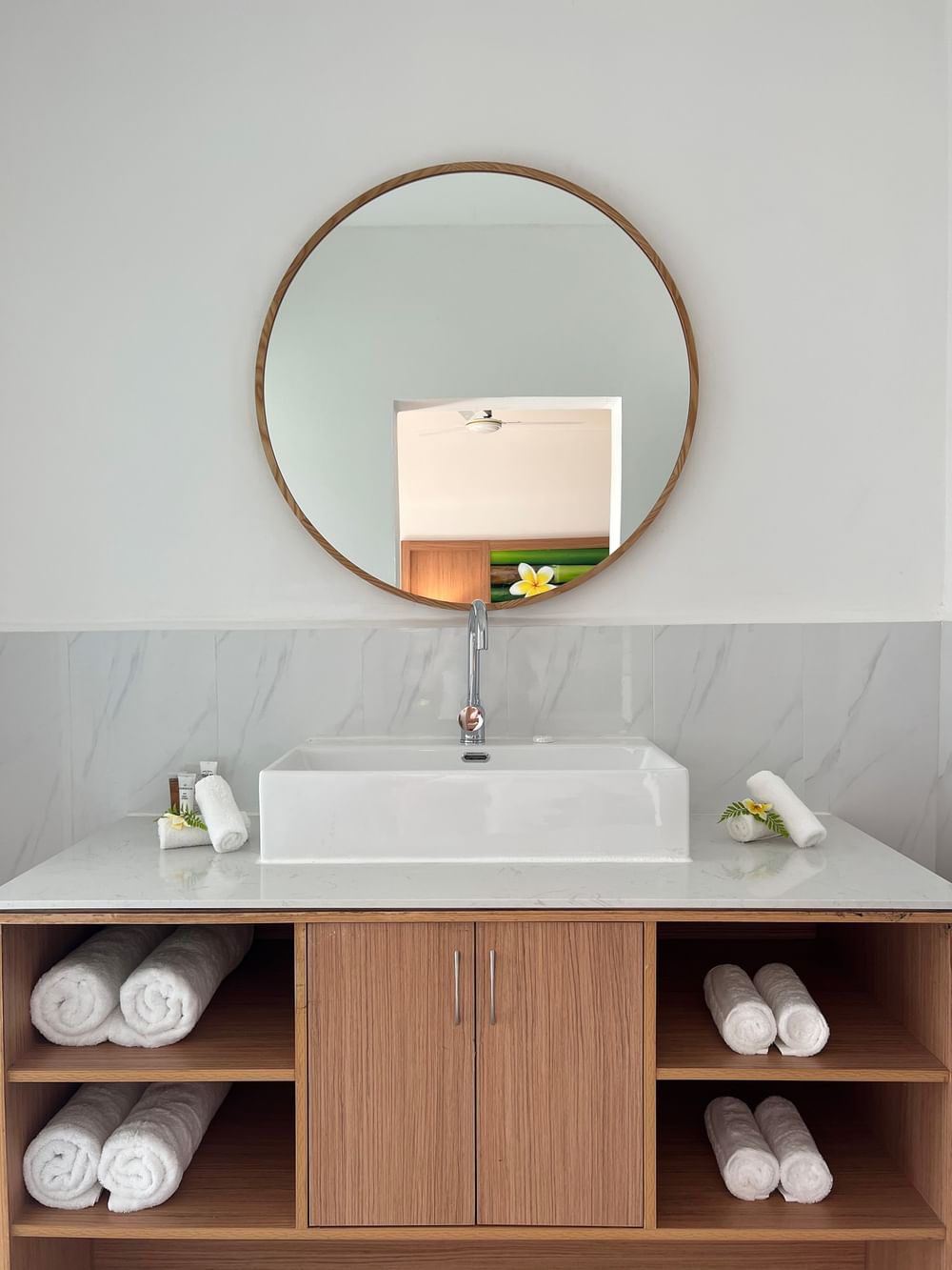 White bathroom with wooden cabinets, large mirror, and folded towels at Warwick Le Lagon - Vanuatu, Efate.