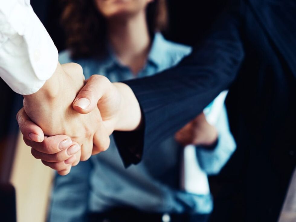 Close-up of a firm handshake between two individuals at Fiesta Americana