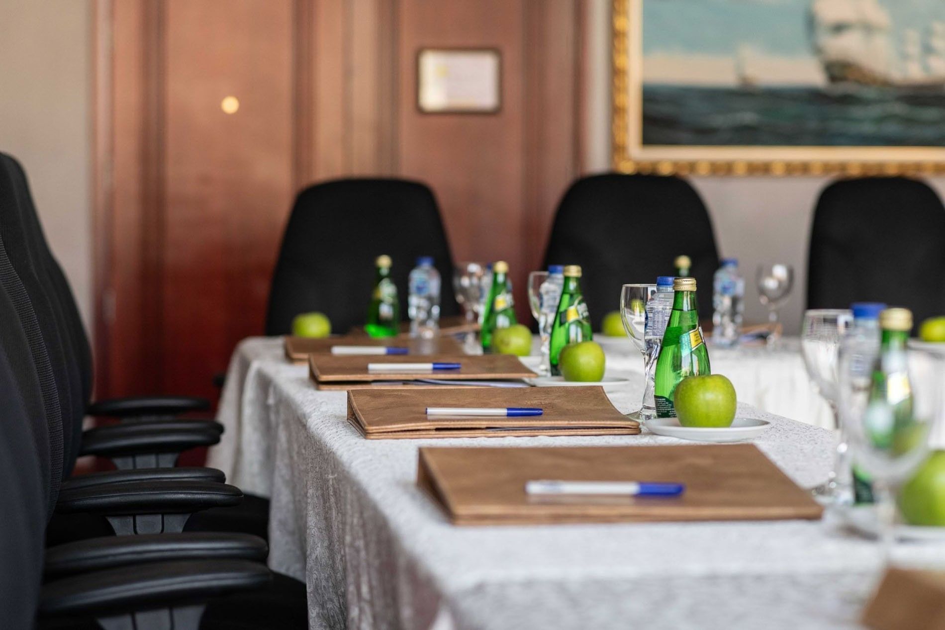 Close-up of a meeting table featuring leather folders and water bottles by black chairs in Al Khaleej at Warwick Al Jubail