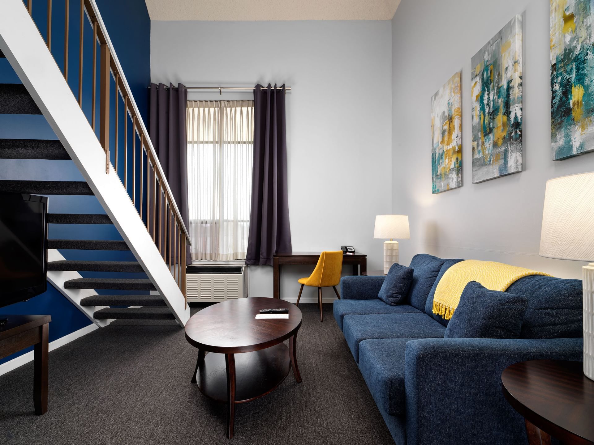 Interior of living room featuring staircase & blue couch in Manchester Suite at Huntingdon Manor