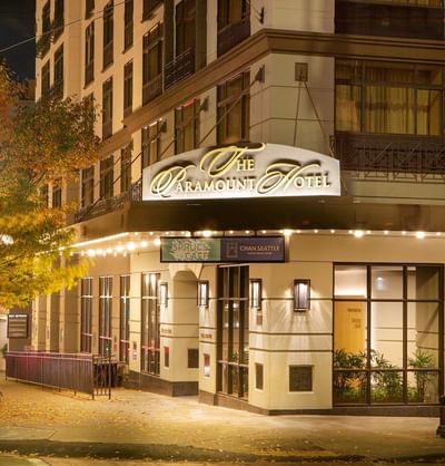 The welcoming, well-lit entrance to The Paramount Hotel Seattle at night, with string lights and fall foliage