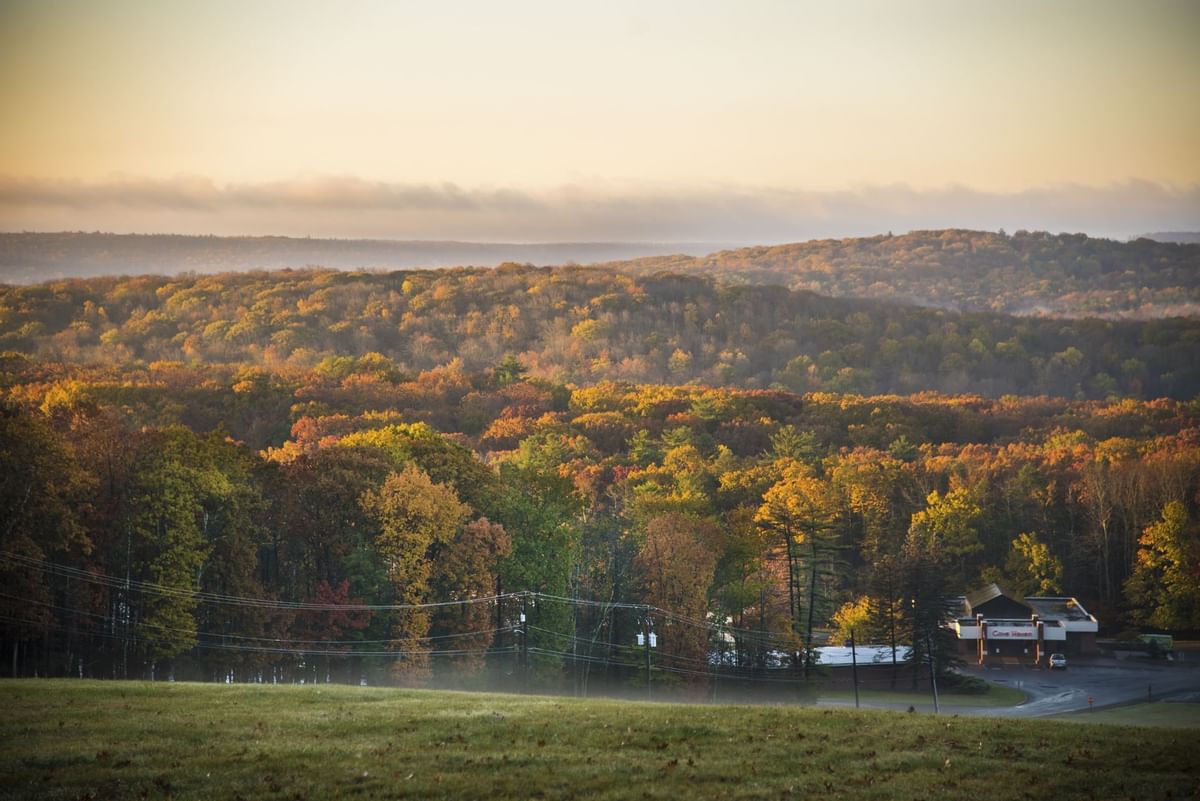 Autumn landscape featuring colorful foliage on rolling hills with a misty foreground near Cove Pocono Resorts