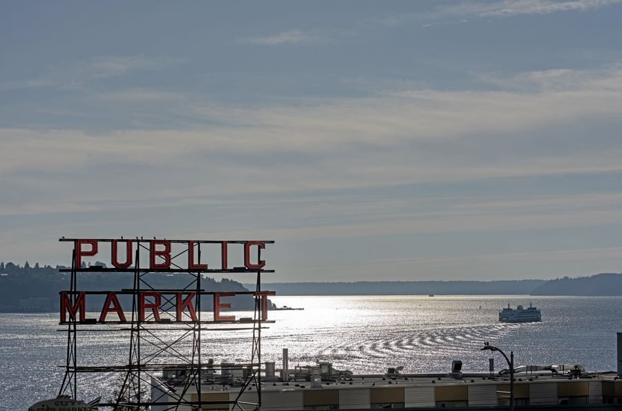 View of Public Market sign over water with a ferry in the distance near Warwick Seattle