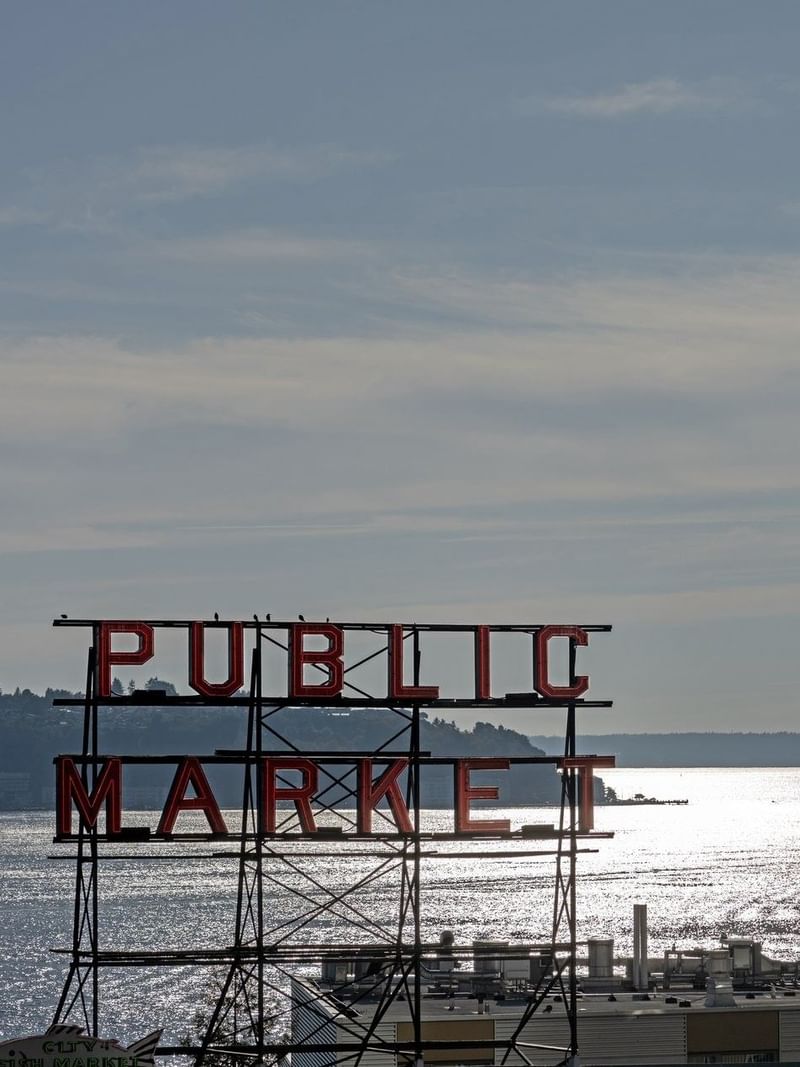 View of Public Market sign over water with a ferry in the distance near Warwick Seattle