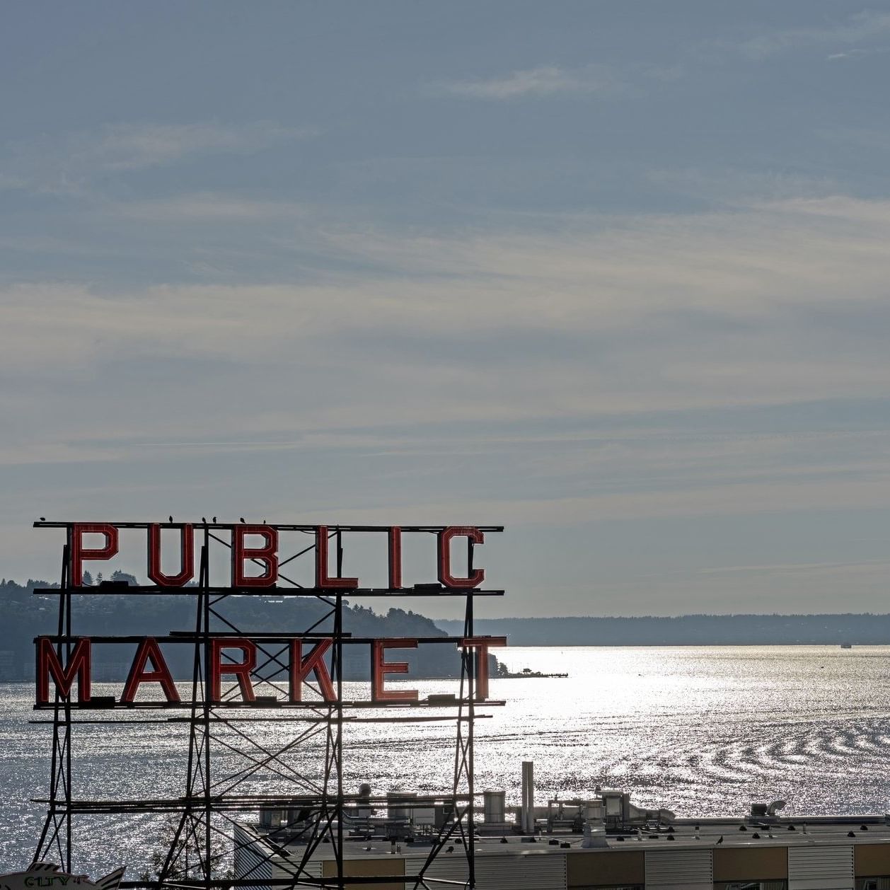 View of Public Market sign over water with a ferry in the distance near Warwick Seattle