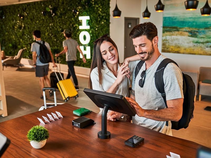 Couple checking in by the digital check-in desk at IOH Hotels