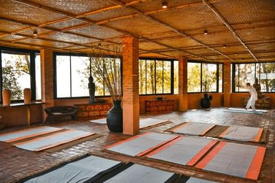 Serene wellness studio with mats arranged on the floor and a person practicing yoga at The Dwarika’s Hotels and Resorts