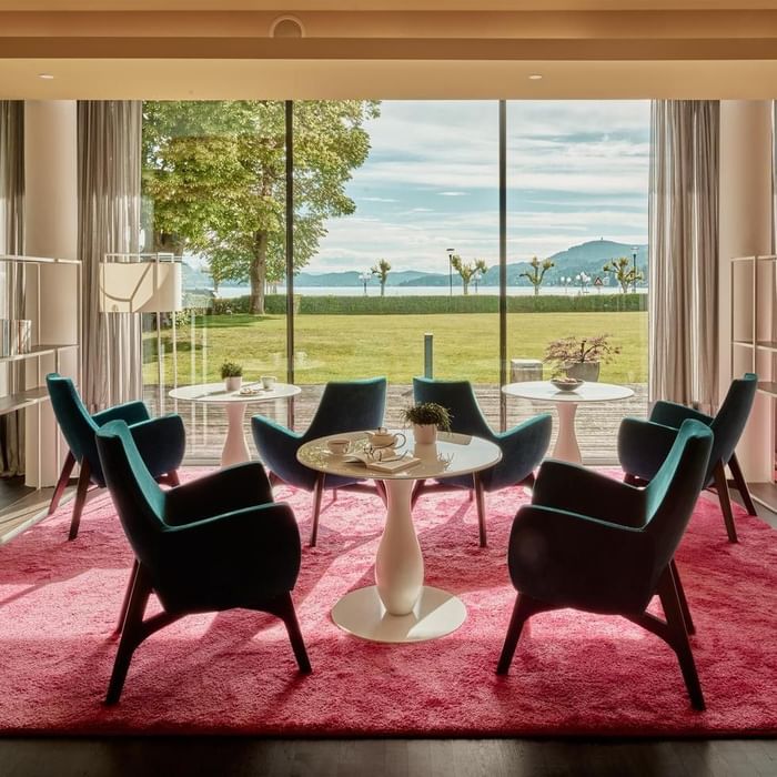 Eleganter Loungebereich mit blauen Sesseln, rotem Teppich und Panoramablick auf die Landschaft.