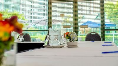 Close-up of a meeting table with glasses & flowers in the Chevalier Room in Chevalier Room at Rosedale on Robson Suite Hotel