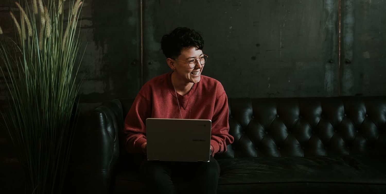 A man sitting and holding a laptop near Calgary Downtown Hotel