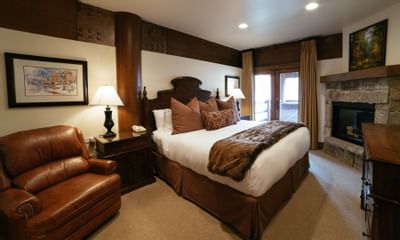A king bed, sofa & a fireplace in a bedroom at Stein Lodge