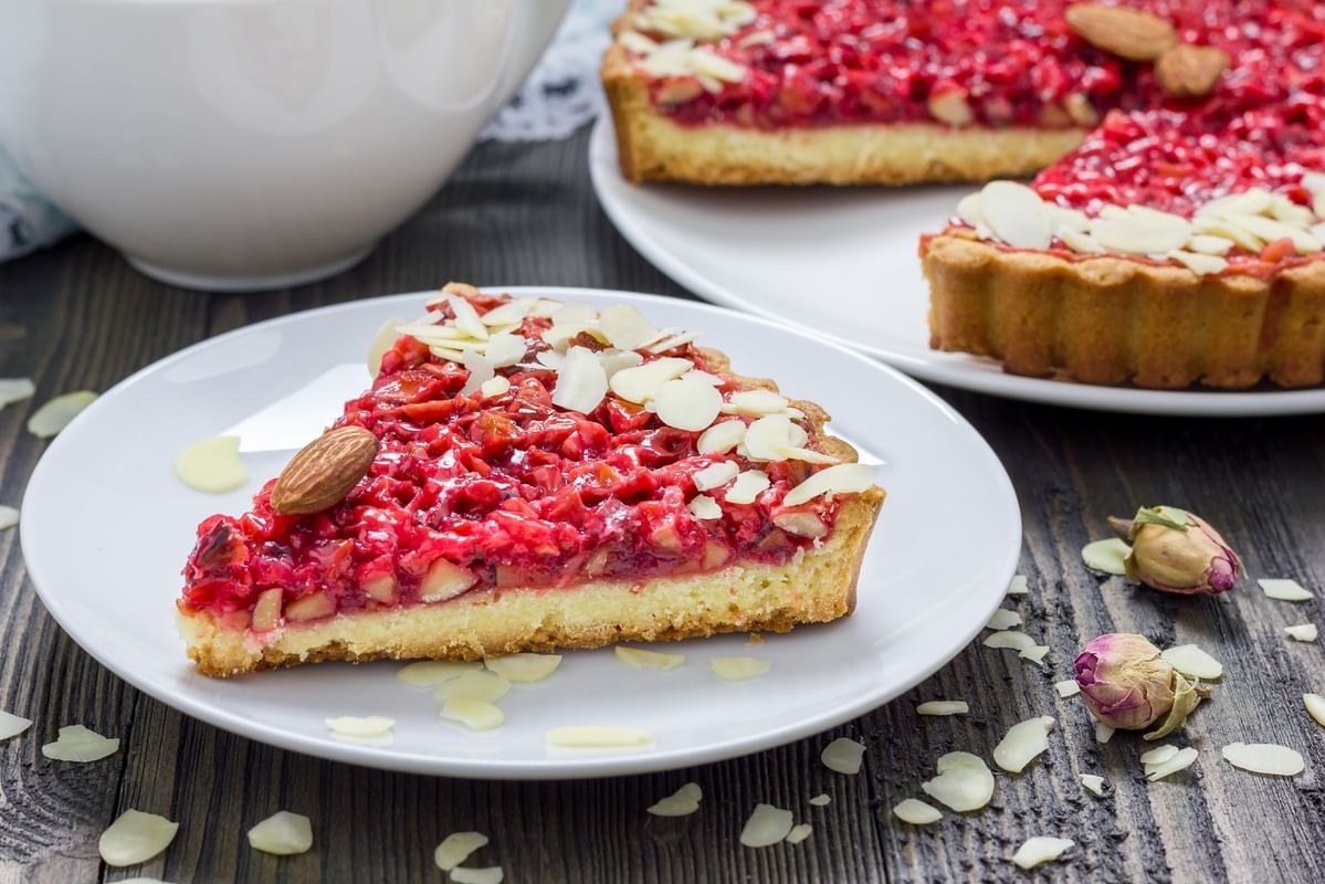Part de tarte aux fruits rouges et amandes effilées sur table en bois au Warwick Reine Astrid-Lyon