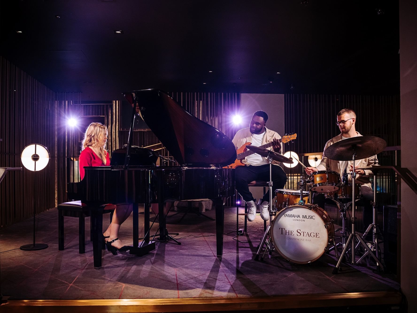 Three people performing a live band show on a stage at The Londoner Hotel