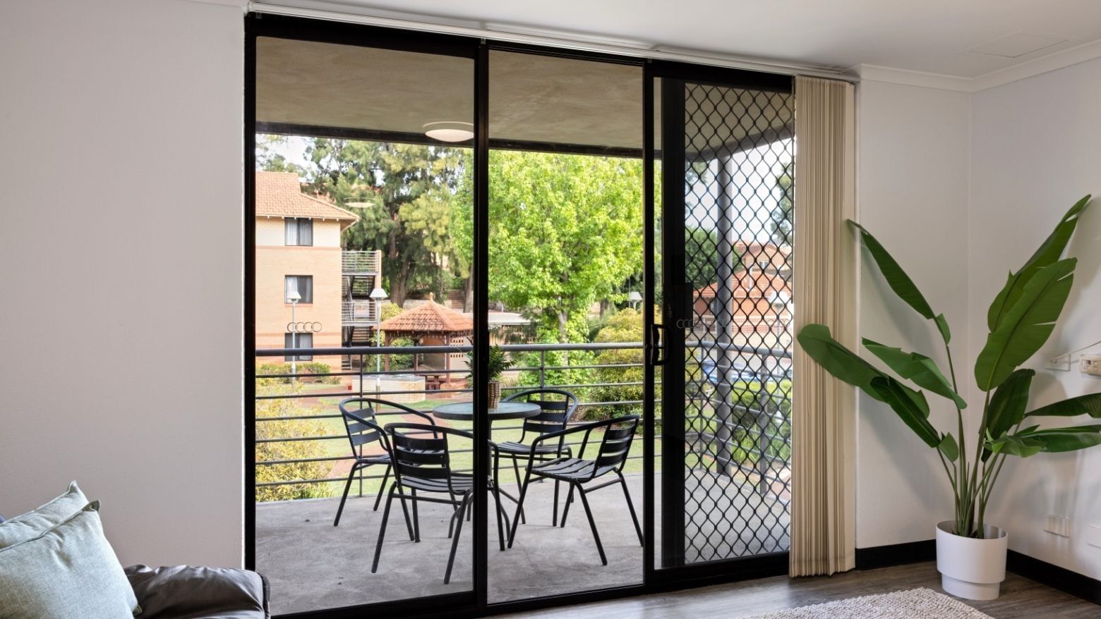 Glass balcony with table and chairs, and a potted plant inside, at UniLodge at Curtin University - Erica Underwood House.