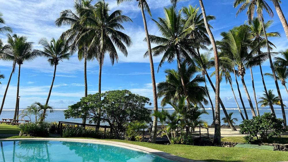 Pool overlooking the beach and ocean with tropical trees at Tambua Sands Beach Resort in Sigatoka.