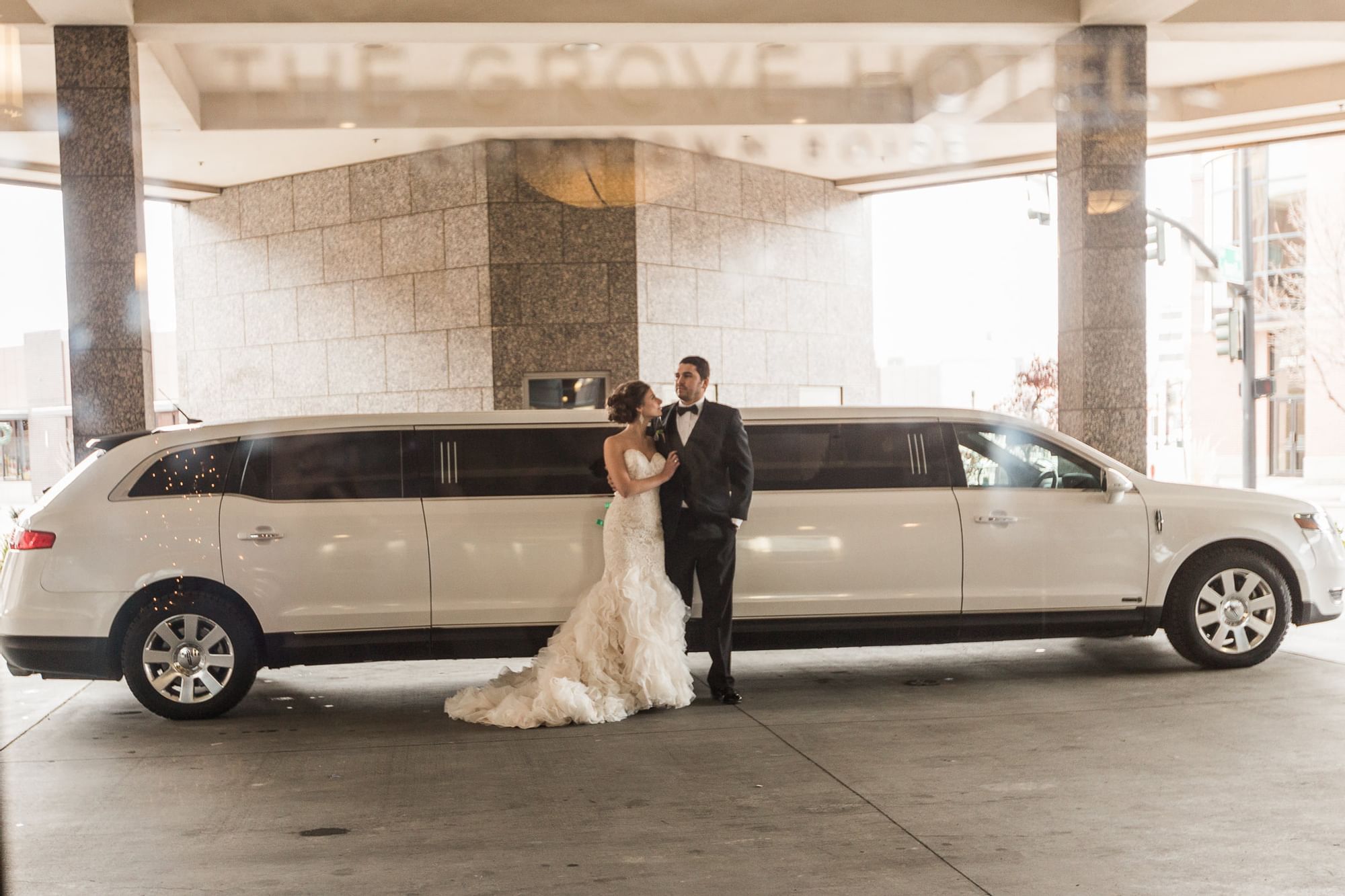 A bride & groom in front of a limo  at The Grove Hotel